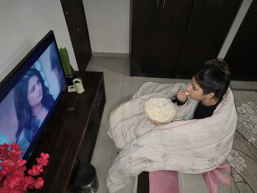 Junge Frau schaut eine Serie über IPTV im Schlafzimmer